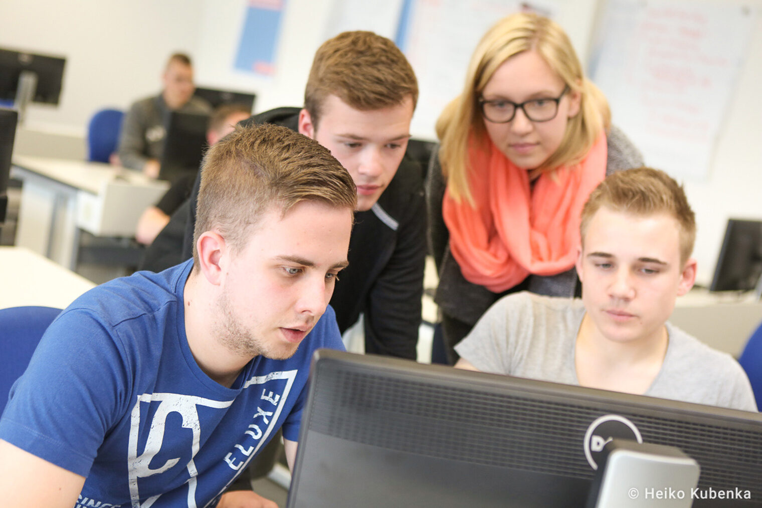 Auszubildende befinden sich in einem Seminarraum und schauen gemeinsam auf einen Monitor.