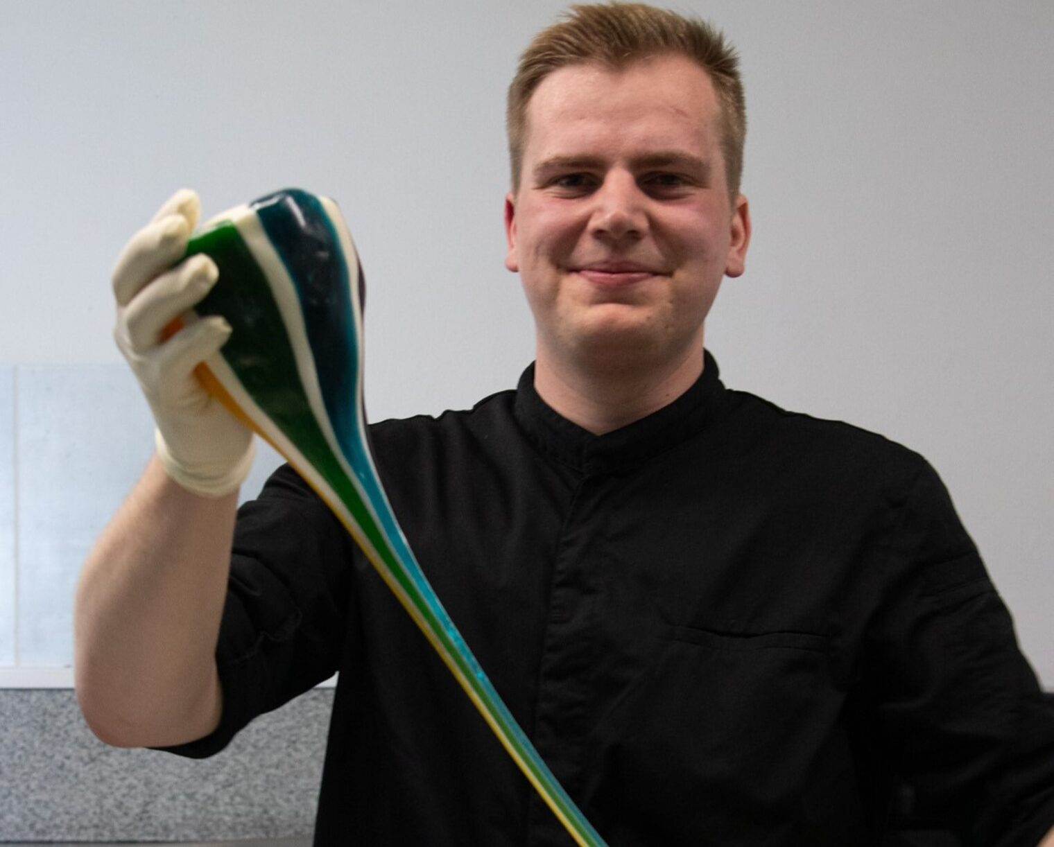 Nils Thiede wird bei der Rockbonbonherstellung gezeigt. Er zieht die zähe, bunte Süßigkeit auseinander.